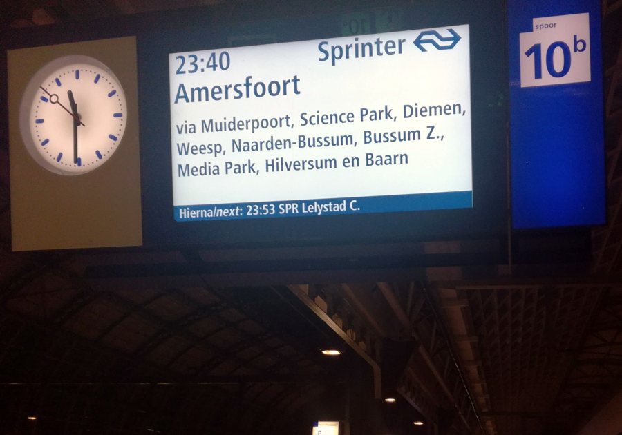 Departure board and clock in a busy railway station